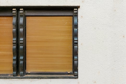 A window with wooden blinds is closed and framed in black trim photo