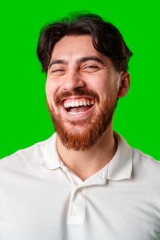 A smiling young man with a beard poses against a bright green background photo