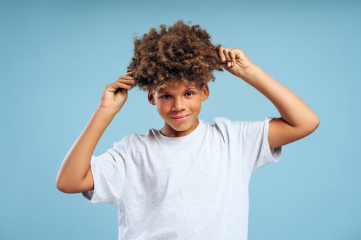Attractive African American boy, teenager touching curly hair looking at camera. Haircare concept photo