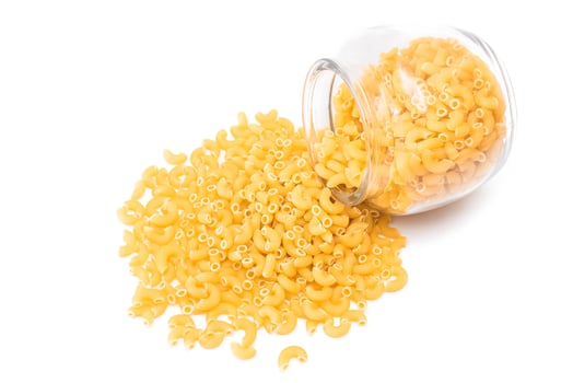 Uncooked Chifferi Rigati Pasta in Glass Jar Isolated on White Background. Fat and Unhealthy Food. Scattered Classic Dry Macaroni. Italian Culture and Cuisine. Raw Pasta photo