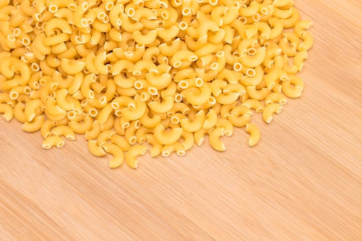 A Heap of Uncooked Chifferi Rigati Pasta on Wooden Kitchen Board. Fat and Unhealthy Food. Classic Dry Macaroni. Italian Culture and Cuisine. Raw Pasta photo