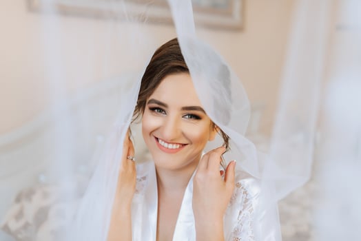 A bride is smiling and posing for a picture with her veil pulled back photo