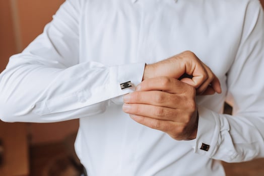 A man is getting ready to dress up in a white shirt and is adjusting his cuff photo