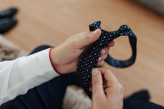 A man is holding a tie and looking at it photo