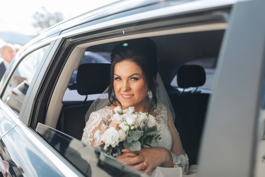 A bride is sitting in a car with a bouquet of flowers photo