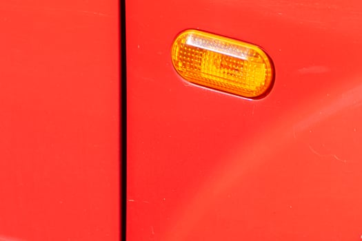 Driver side headlights on a car. close-up view of the front side flasher of a red car photo