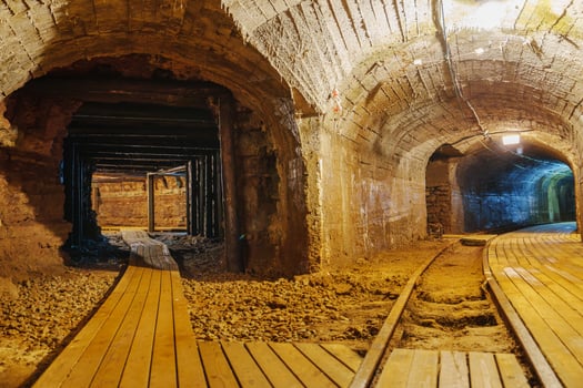 Venture into the depths of an old abandoned mine tunnel, where shadows dance along the wooden walkway and rusty tracks evoke a sense of mystery and exploration in this long-forgotten place. photo