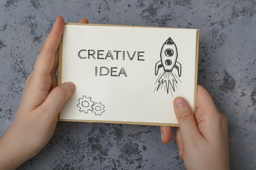 A hand holding a piece of paper with the word creative on it photo