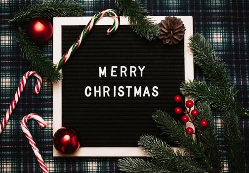 Merry Christmas lettering in plastic letters on an old vintage letter board. There are caramel canes, balls, cones and fir branches all around. Top view. Flatley. Ready-made Christmas greeting card. photo