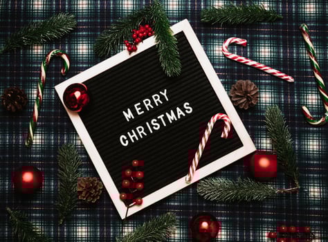 Merry Christmas lettering in plastic letters on an old vintage letter board. On the background there are caramel canes, balls, cones and fir branches. Top view. Flatley. Christmas greeting card. photo