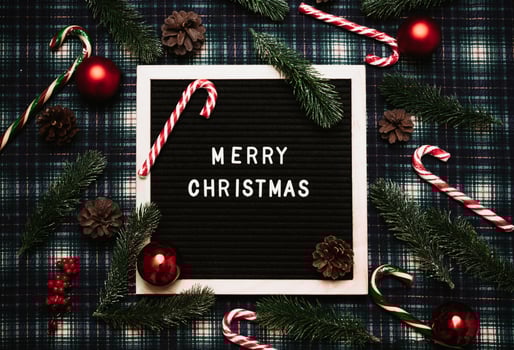 Merry Christmas lettering in plastic letters on an old vintage letter board. There are caramel canes, balls, cones and fir branches all around. Top view. Flatley. Ready-made Christmas greeting card. photo