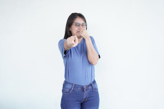 beautiful Asian woman shows a wrinkled nose in reaction to a smell while covering her nose against a white background photo