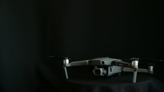 A small gray drone sitting on top of a black table photo