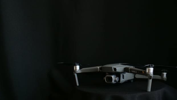 A small gray drone sitting on top of a black table photo