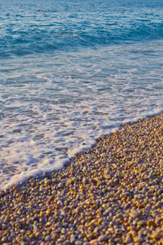 Pebble stones by the sea. Waves of blue Tyrrhenian sea. photo
