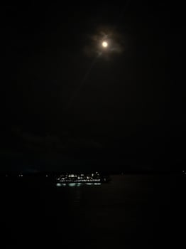 A boat is in the water at night with a full moon photo