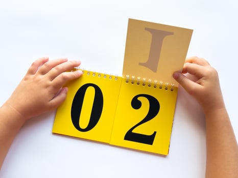 Childs hands flipping educational flashcards with numbers and letters on bright yellow background photo