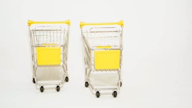 Two yellow shopping carts with wheels on a white background photo