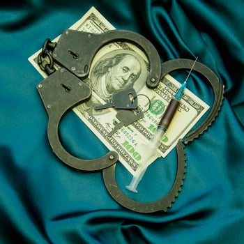 Handcuffs and money on a blue satin cloth photo
