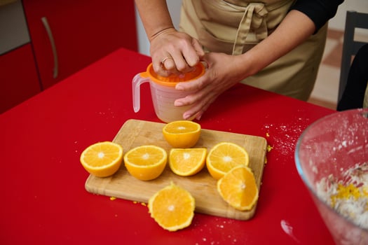 Juicing fresh oranges on a red kitchen counter for breakfast photo