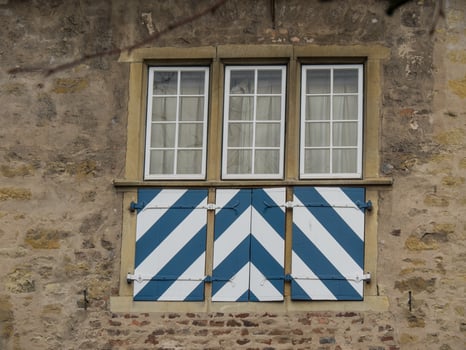 A window with a blue and white striped shutters photo