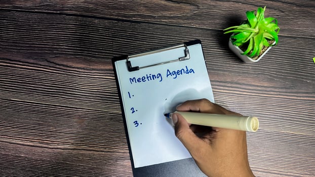 Concept of Meeting Agenda write on paperwork Supported by an additional services isolated on wooden background. photo