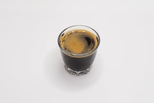 Black Espresso Shot in a Clear Glass on Minimalist White. photo