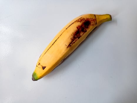 Ripe banana with brown spots on white background photo
