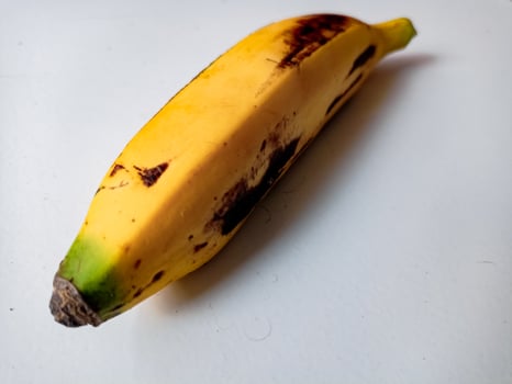 Ripe banana with brown spots on white background photo