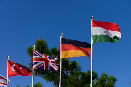Waving flags of Turkey, the United Kingdom, Germany, and Hungary under a clear blue sky at a vibrant outdoor location photo