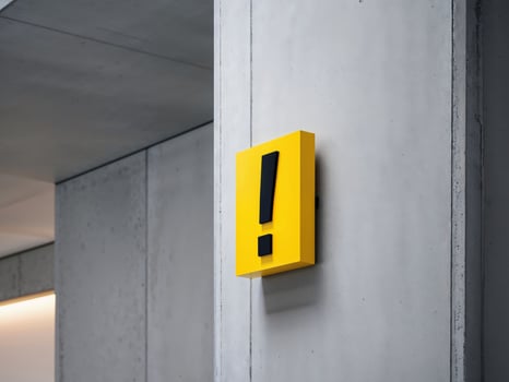 Yellow exclamation sign on the wall of a building photo