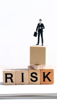 businessman standing on a stack blocks spelling 'risk' photo