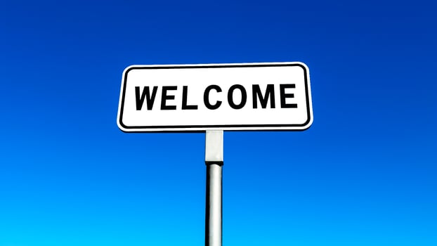 white welcome sign against a blue sky photo