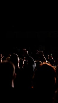 crowd reaches upward a dark concert venue photo