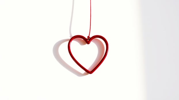 red heart ornament hanging against a white background photo