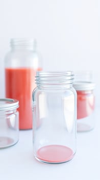 clear glass jar with pink liquid two blurred jars photo