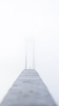 solitary figure walks through fog on a bridge photo