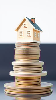 small yellow house rests atop a stack gold coins photo