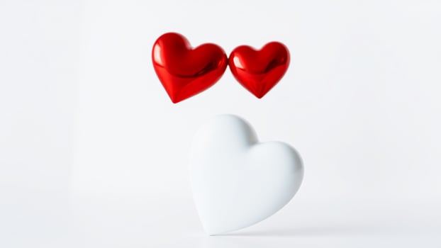 two red hearts float above a white ceramic heart photo