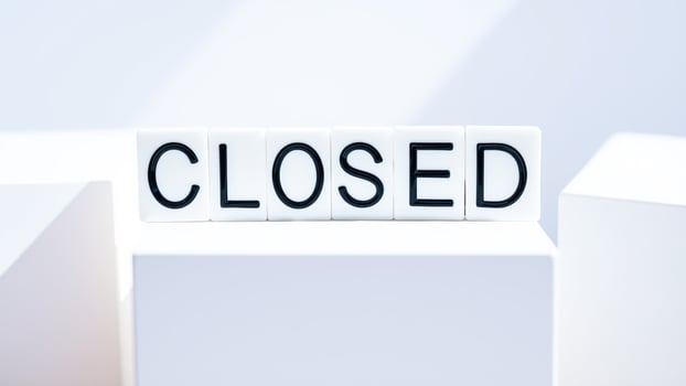 black letter tiles spell closed on a white background photo
