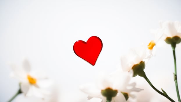 red glass heart surrounded by white flowers photo