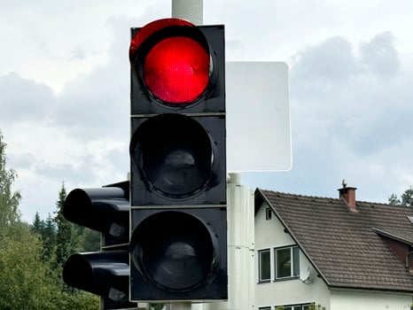 Red traffic light at intersection on cloudy day with empty street in background photo
