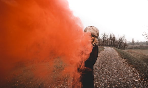 beautiful middle-aged woman on a country road showing a lantern that releases red smoke photo