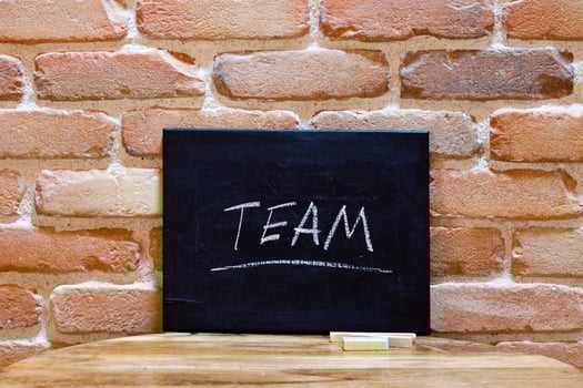 Blackboard with the word Team drown by hand on wooden table on brick wall background. photo