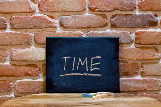 Black board with the word Time drown by hand on wooden table on brick wall background. photo