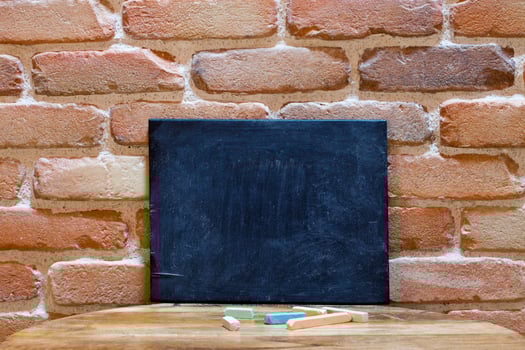 Blank blackboard on wooden table at brick wall. photo