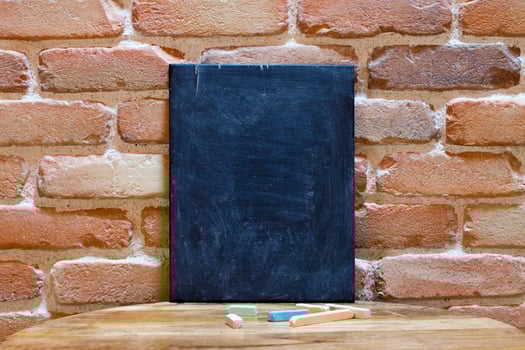 Blank blackboard on wooden table at brick wall. photo