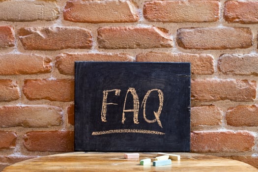 Black board with the word FAQ drown by hand on wooden table on brick wall background. photo