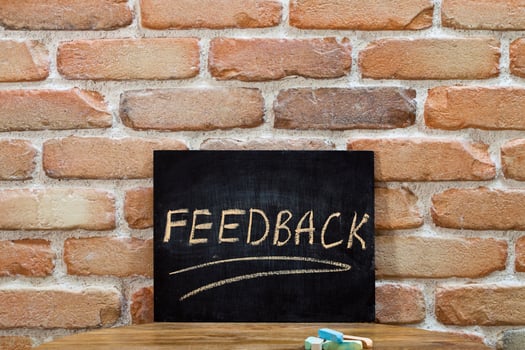 Chalk board with the word FEEDBACK drown by hand and chalks on wooden table on brick wall background. photo