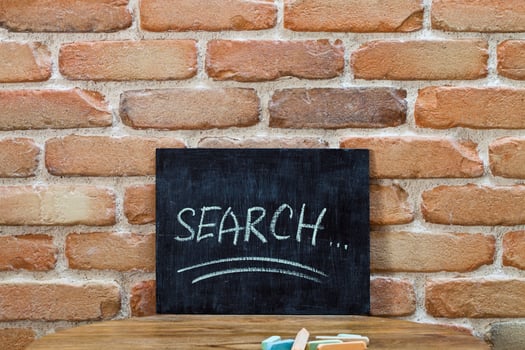 Chalk board with the word SEARCH drown by hand and chalks on wooden table on brick wall background. photo